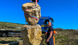 Installation of a stone sculpture in a field with blue skies