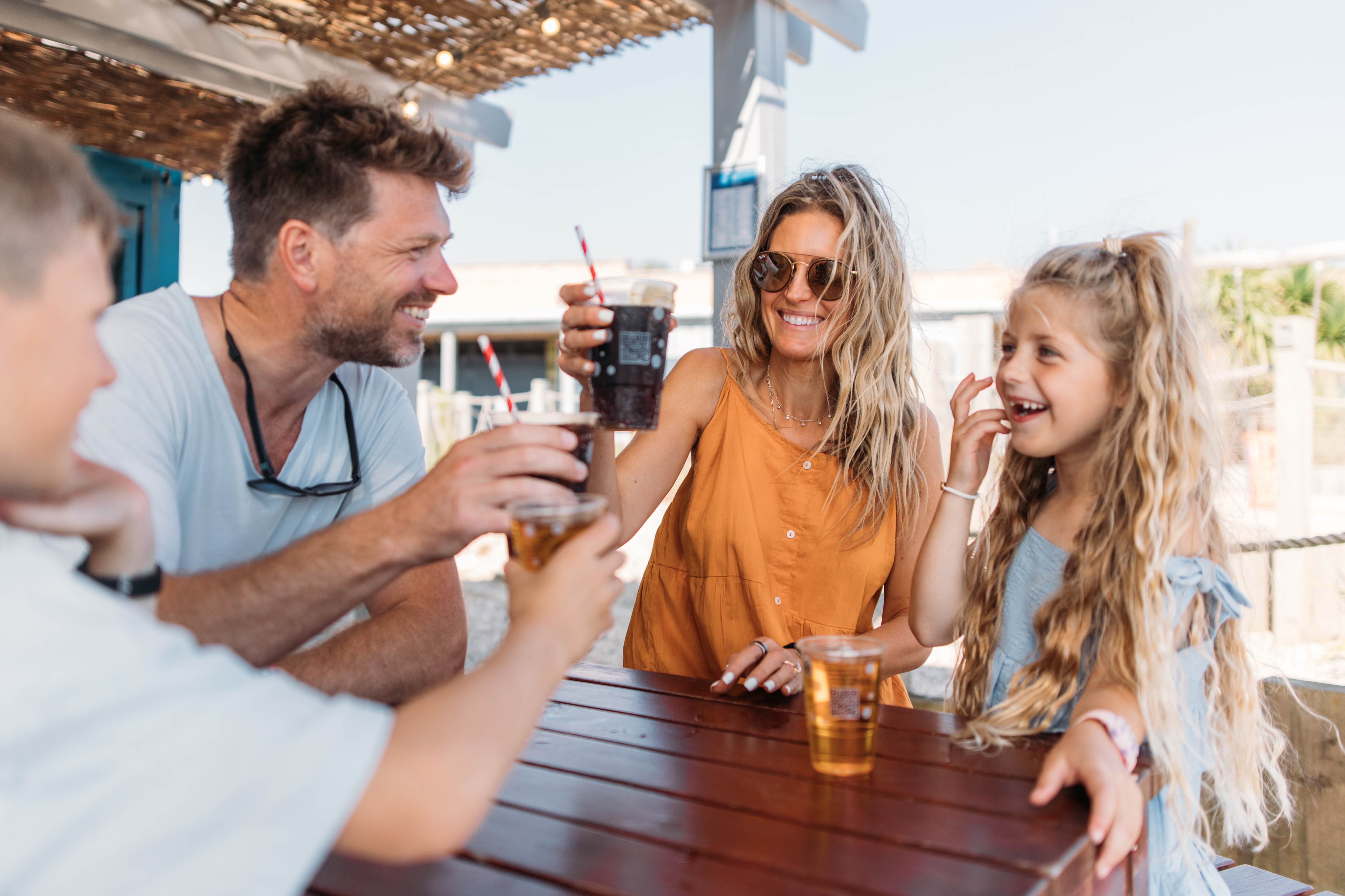 Family cheers with drinks bought from outdoor bar at holiday park