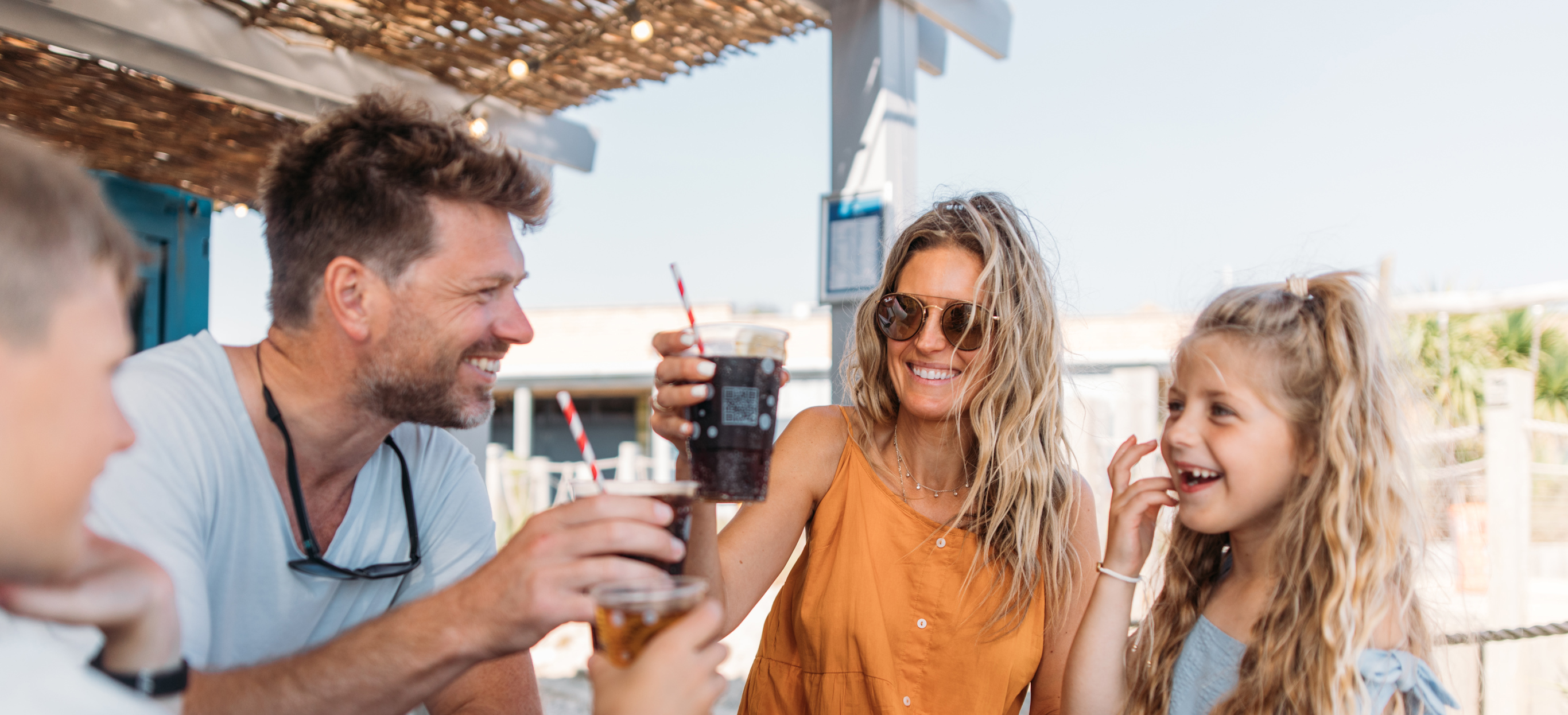 Family cheers with drinks bought from outdoor bar at holiday park