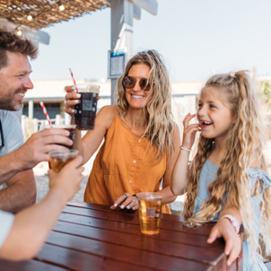 Family cheers with drinks bought from outdoor bar at holiday park