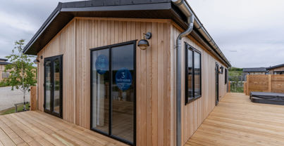 External of a luxury lodge on pitch with decking and hot tub