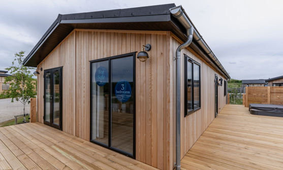 External of a luxury lodge on pitch with decking and hot tub