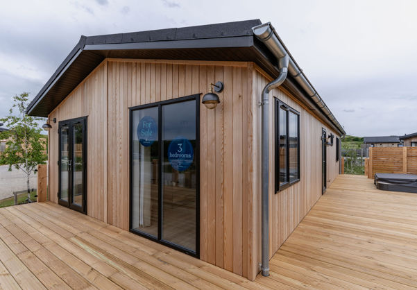 External of a luxury lodge on pitch with decking and hot tub