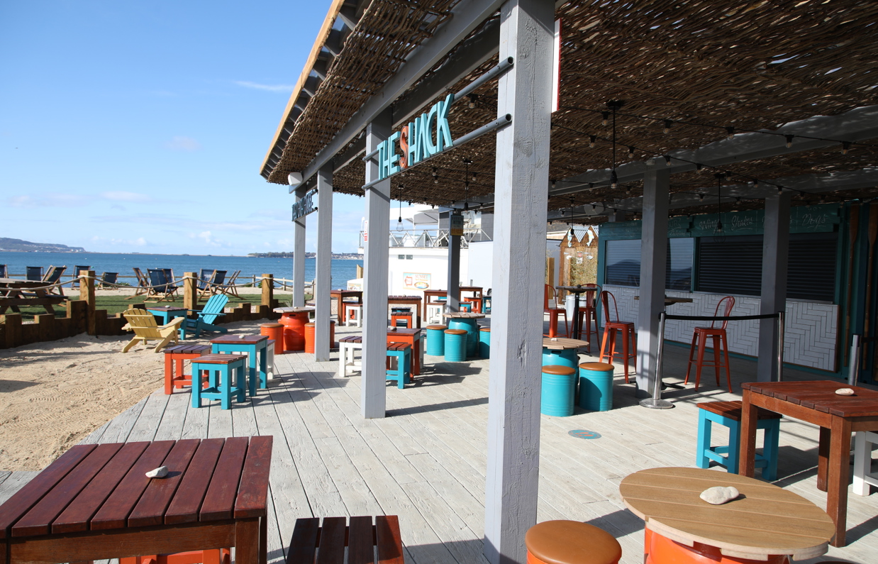 An outdoor beach bar and street food shack with outdoor seating by the sea