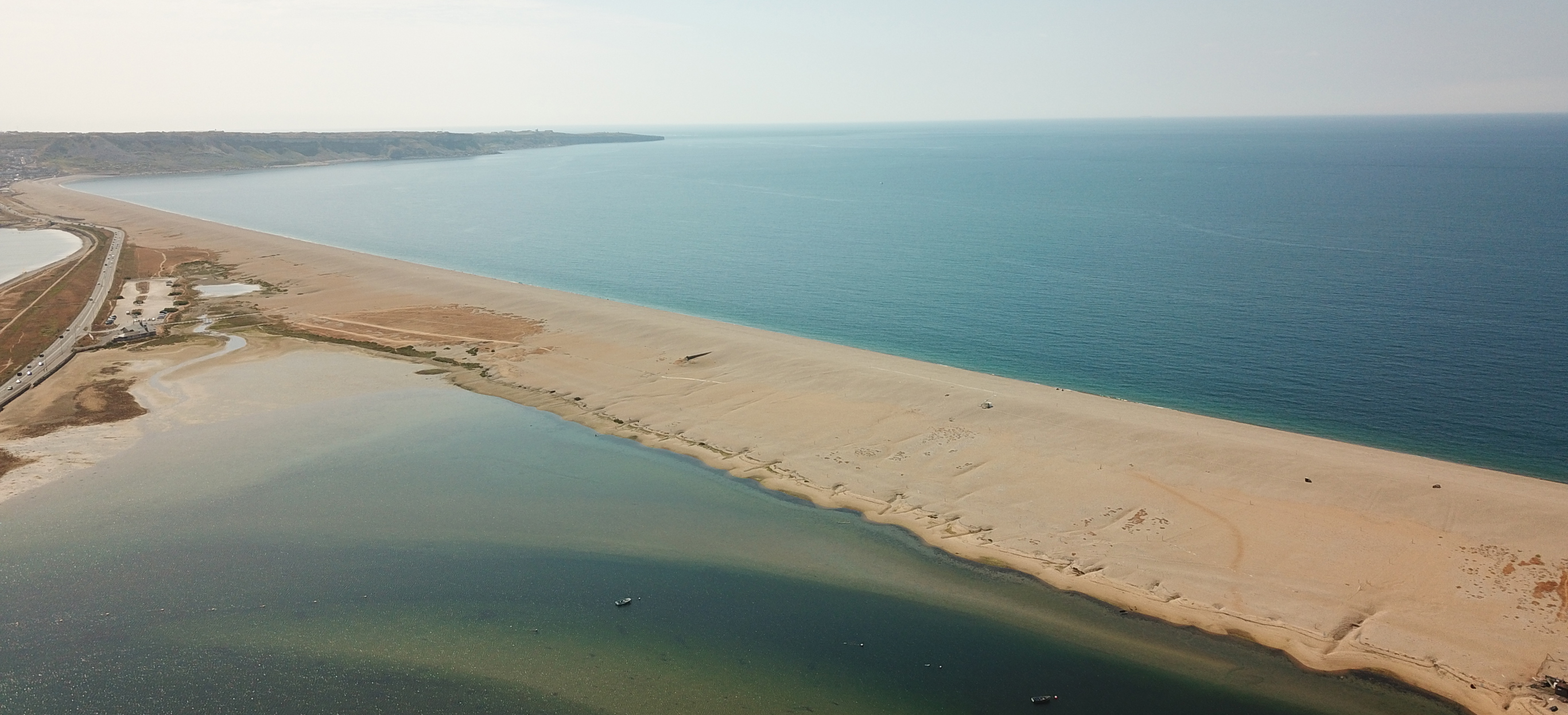 Aerial view of a stretch of Chesil Beach looking out towards the sea and Portland