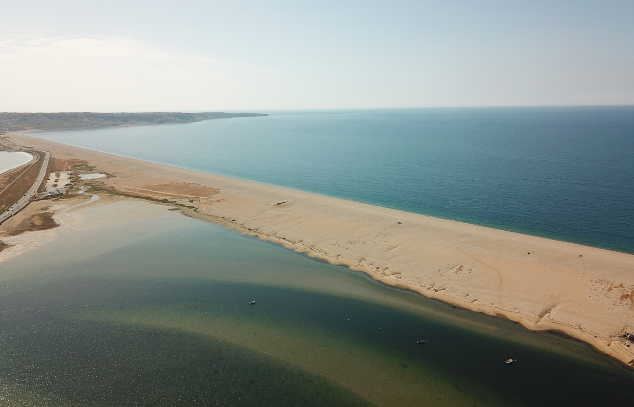 Aerial view of a stretch of Chesil Beach looking out towards the sea and Portland