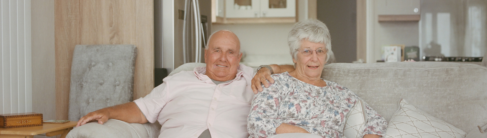 An older couple sat together on a sofa in a holiday home