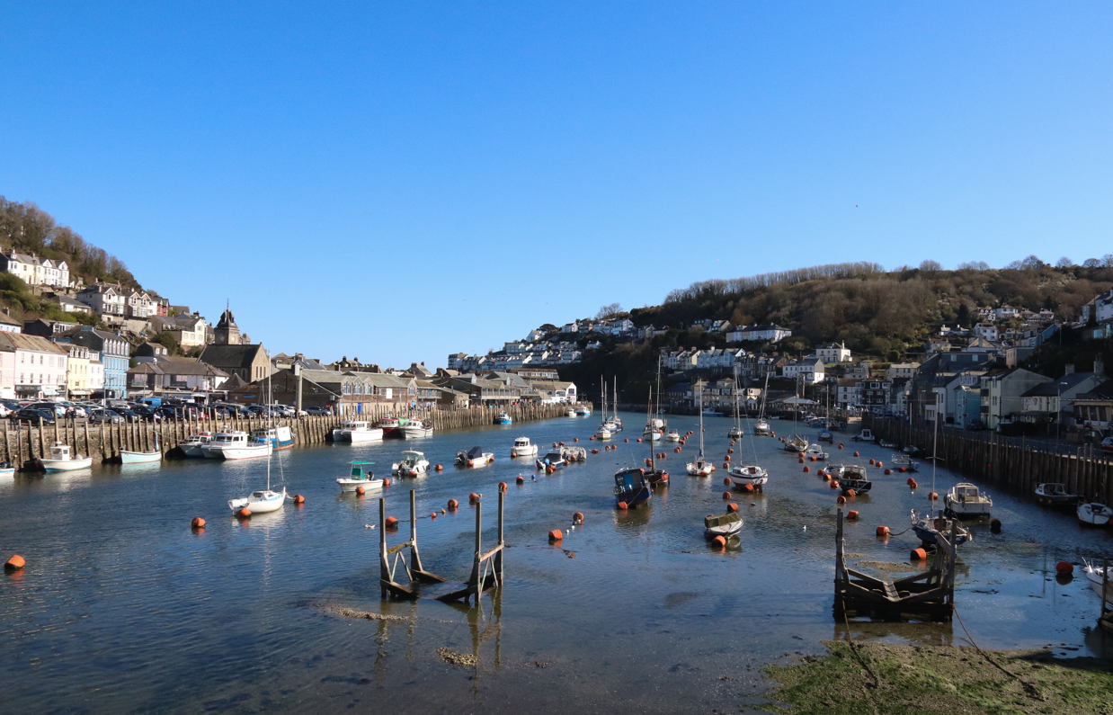 Looe Harbour with various ships on the water on a sunny, blue sky day