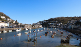 Looe Harbour with various ships on the water on a sunny, blue sky day