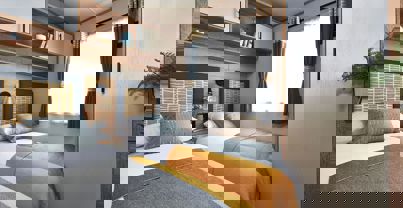 Twin room with cosy bedding, compact self-contained wardrobe, and shelving above the bed