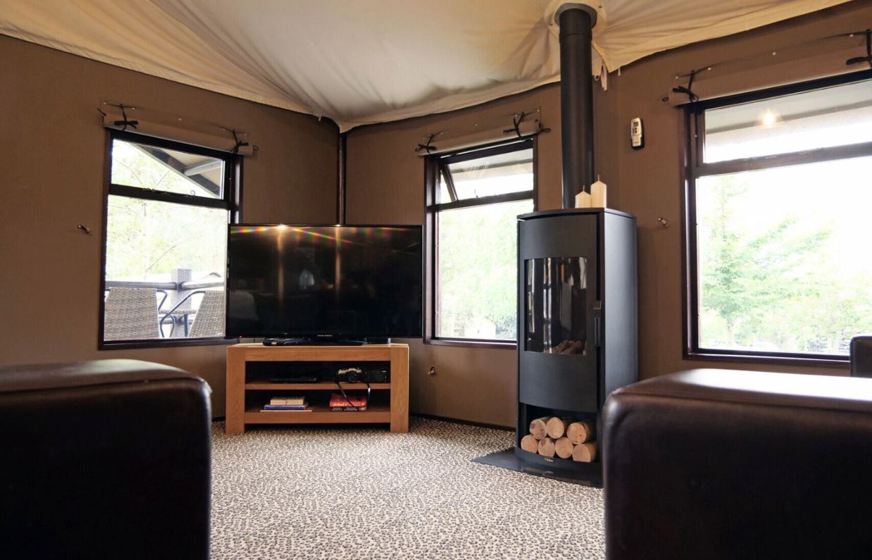 Internal of safari tent open plan lounge with log fire