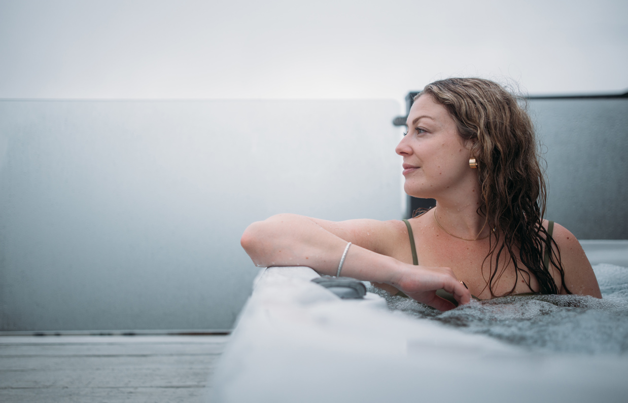 A woman looking peaceful and relaxed in a hot tub looking out towards the view