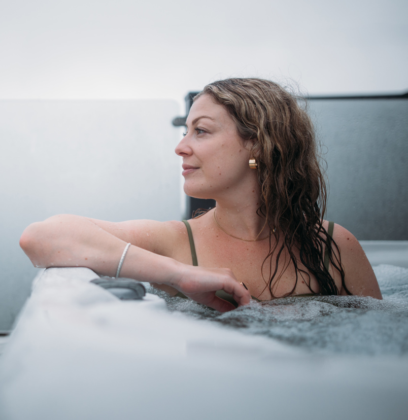A woman looking peaceful and relaxed in a hot tub looking out towards the view
