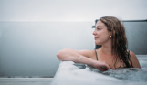 A woman looking peaceful and relaxed in a hot tub looking out towards the view