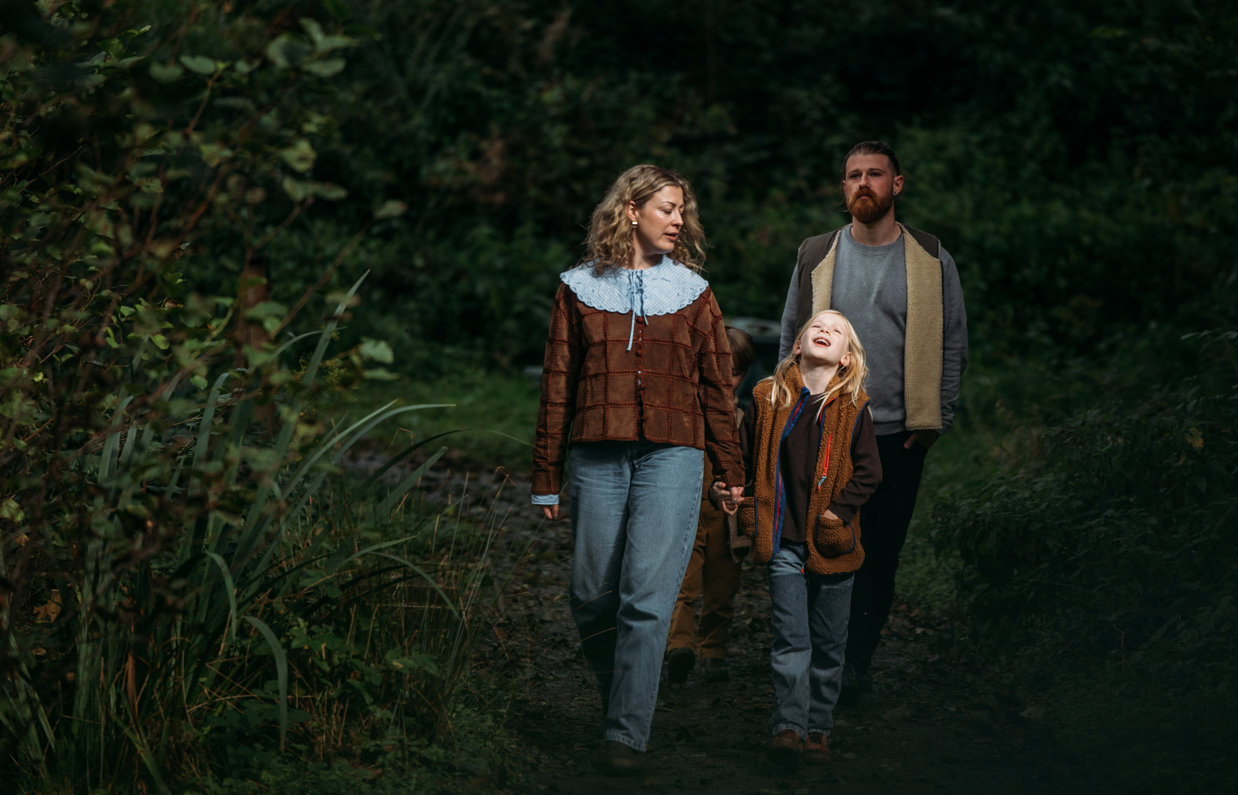 A couple with a young boy walking through the woods in the dark