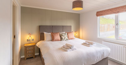 Master bedroom with large comfy grey bed and sage green feature wall