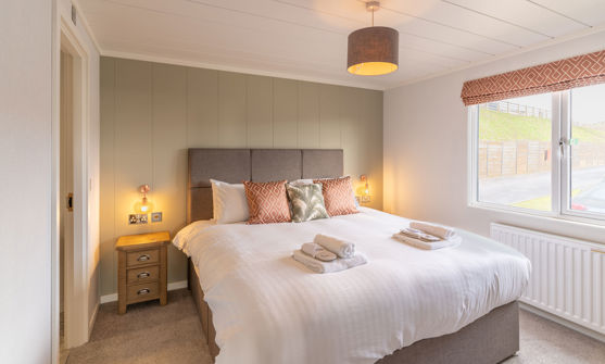 Master bedroom with large comfy grey bed and sage green feature wall