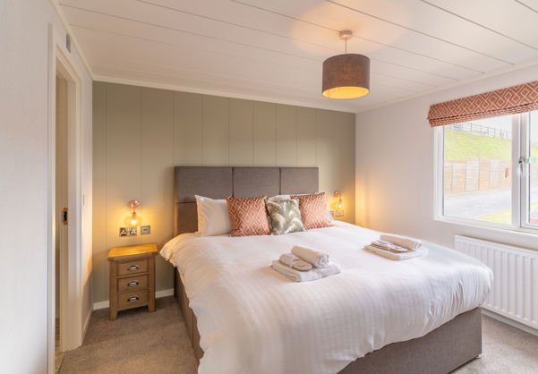 Master bedroom with large comfy grey bed and sage green feature wall