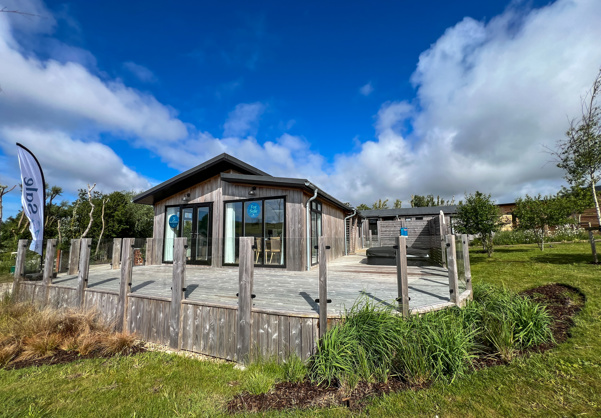 External of a luxury lodge on pitch with decking and hot tub