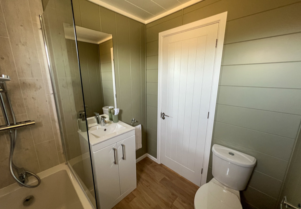 Internal of a luxury lodge bathroom with shower over bath, toilet and sink