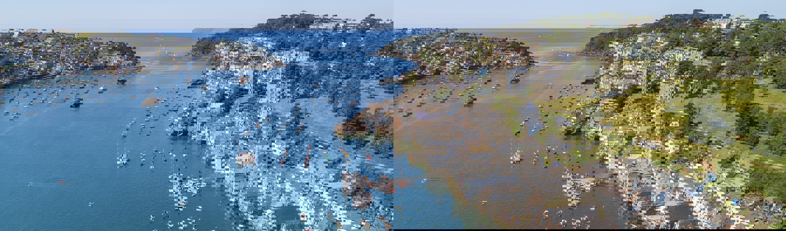 Fowey town and harbour from above with blue waters out to sea