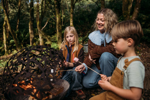Mother toasts marshmallows with her sons in woodland