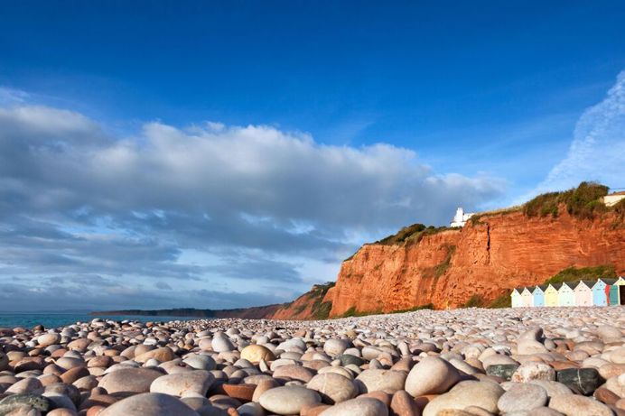Pebble beach with rocky grassy headland and beach huts