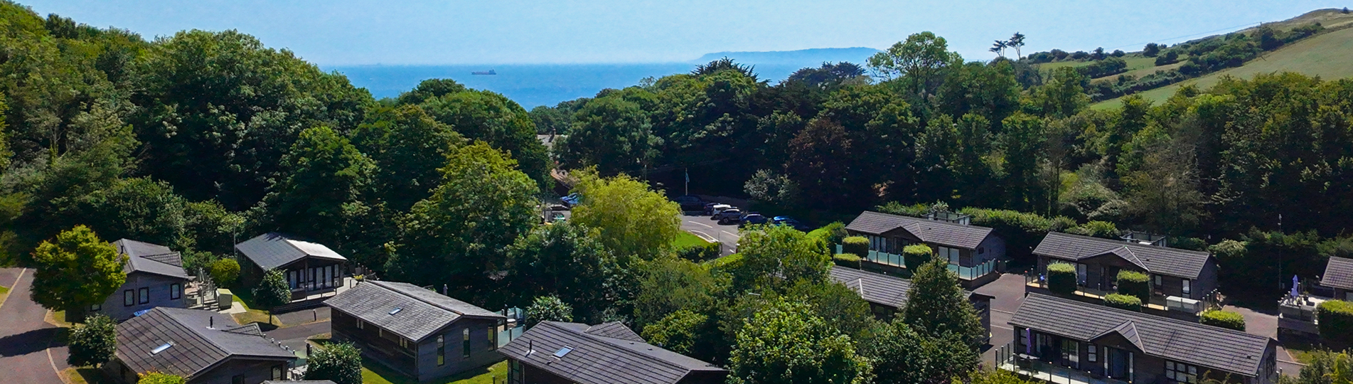 Osmington Mills Lodge Park from above with views of the sea and Portland in the distance