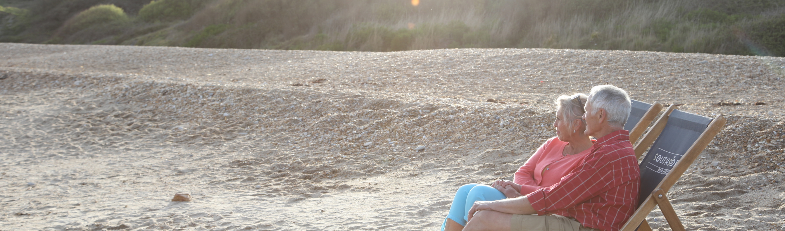 Older couple relax on deckchairs on  Weymouth Beach