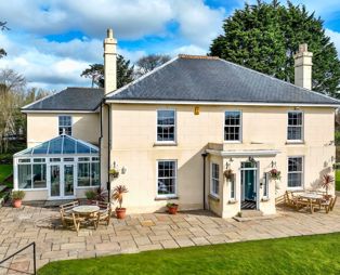 External of a manor house with conservatory, outside seating, grass areas and a hot tub