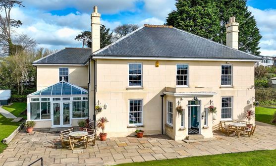 External of a manor house with conservatory, outside seating, grass areas and a hot tub