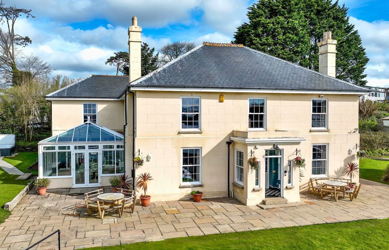 External of a manor house with conservatory, outside seating, grass areas and a hot tub