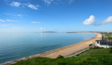 The view of sweeping Weymouth Bay on a sunny, blue sky day with serene blue water