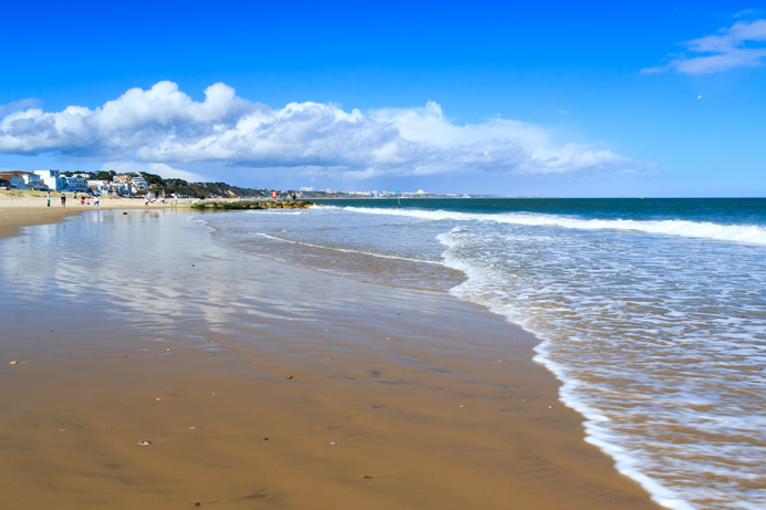 A sandy beach at low tide with blue waters