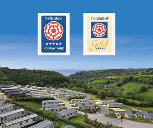 Drone view of Tregoad Holiday Park on a blue sky day with Visit England award graphics overlaid