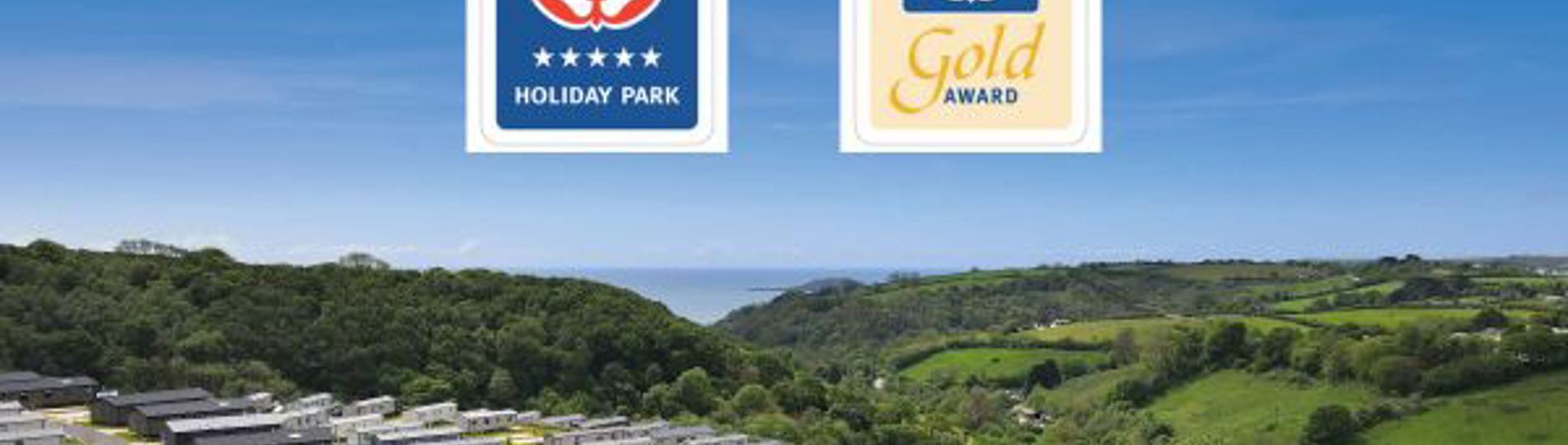 Drone view of Tregoad Holiday Park on a blue sky day with Visit England award graphics overlaid