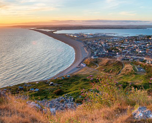 View from the cliff side of Chesil Beach, Portland and Weymouth at sunset