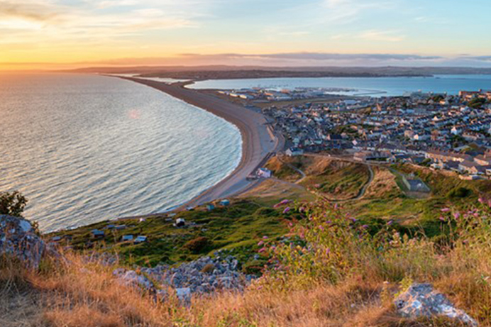 View from the cliff side of Chesil Beach, Portland and Weymouth at sunset