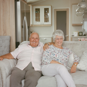 An older couple sat together on a sofa in a holiday home
