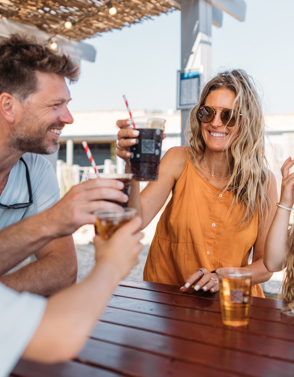 A couple with a young girl and boy at a table outside toasting drinks and smiling
