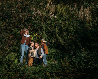 A family of four walking along a nature path among woodland in the sun