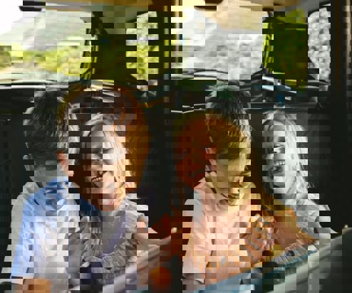 A young boy and girl in the back of a car laughing