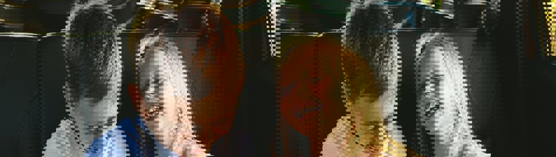 A young boy and girl in the back of a car laughing