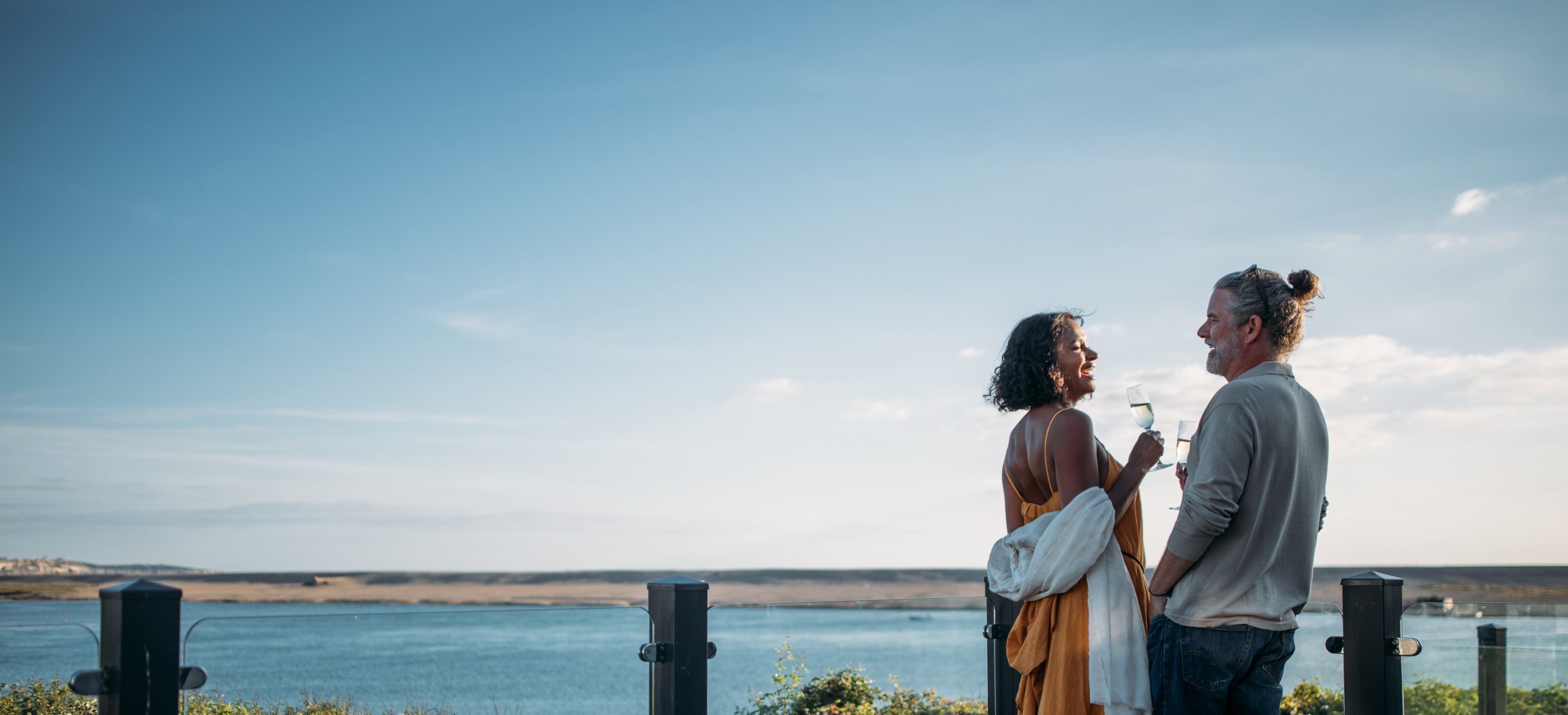 Couple celebrating on deck of holiday home overlooking chesil beach
