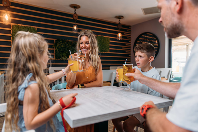 A family of four toasting a drink at a table in Southside Bar & Grill