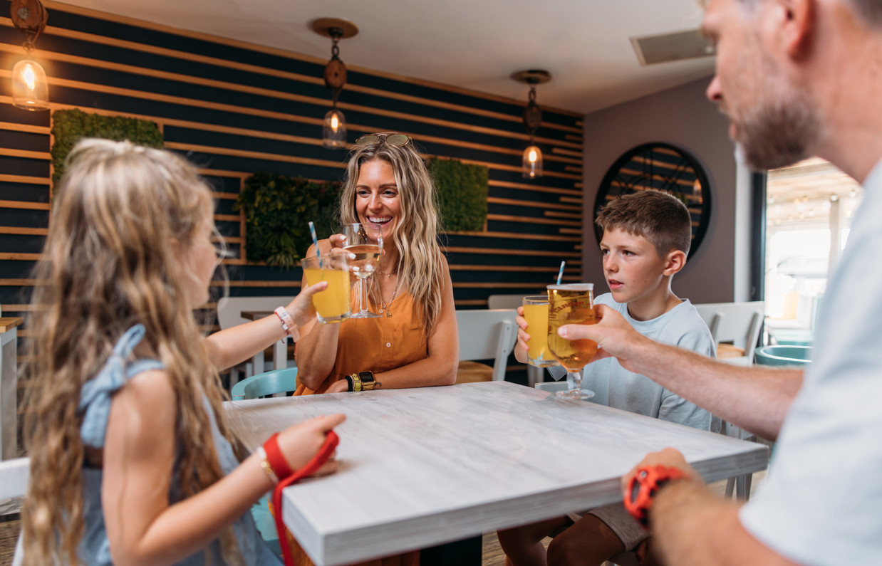 A family of four toasting a drink at a table in Southside Bar & Grill