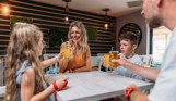 A family of four toasting a drink at a table in Southside Bar & Grill