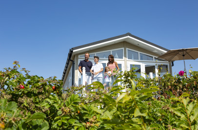 Family on deck of caravan at chesil beach looking out at the view together