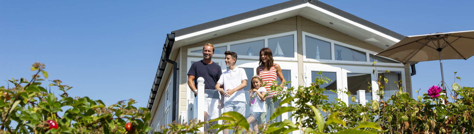 Family on deck of caravan at chesil beach looking out at the view together