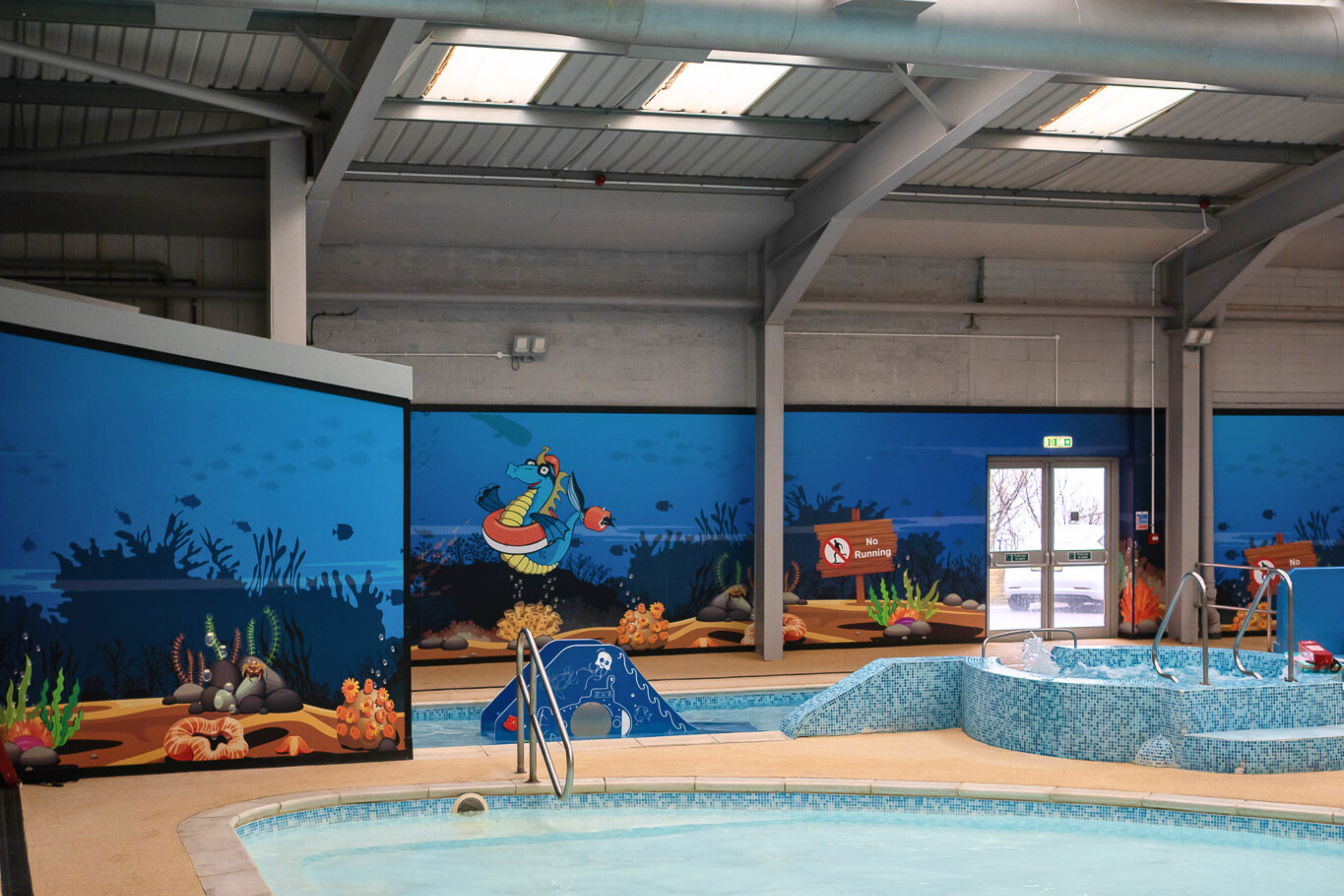 A children's splash zone within a heated indoor swimming pool complex